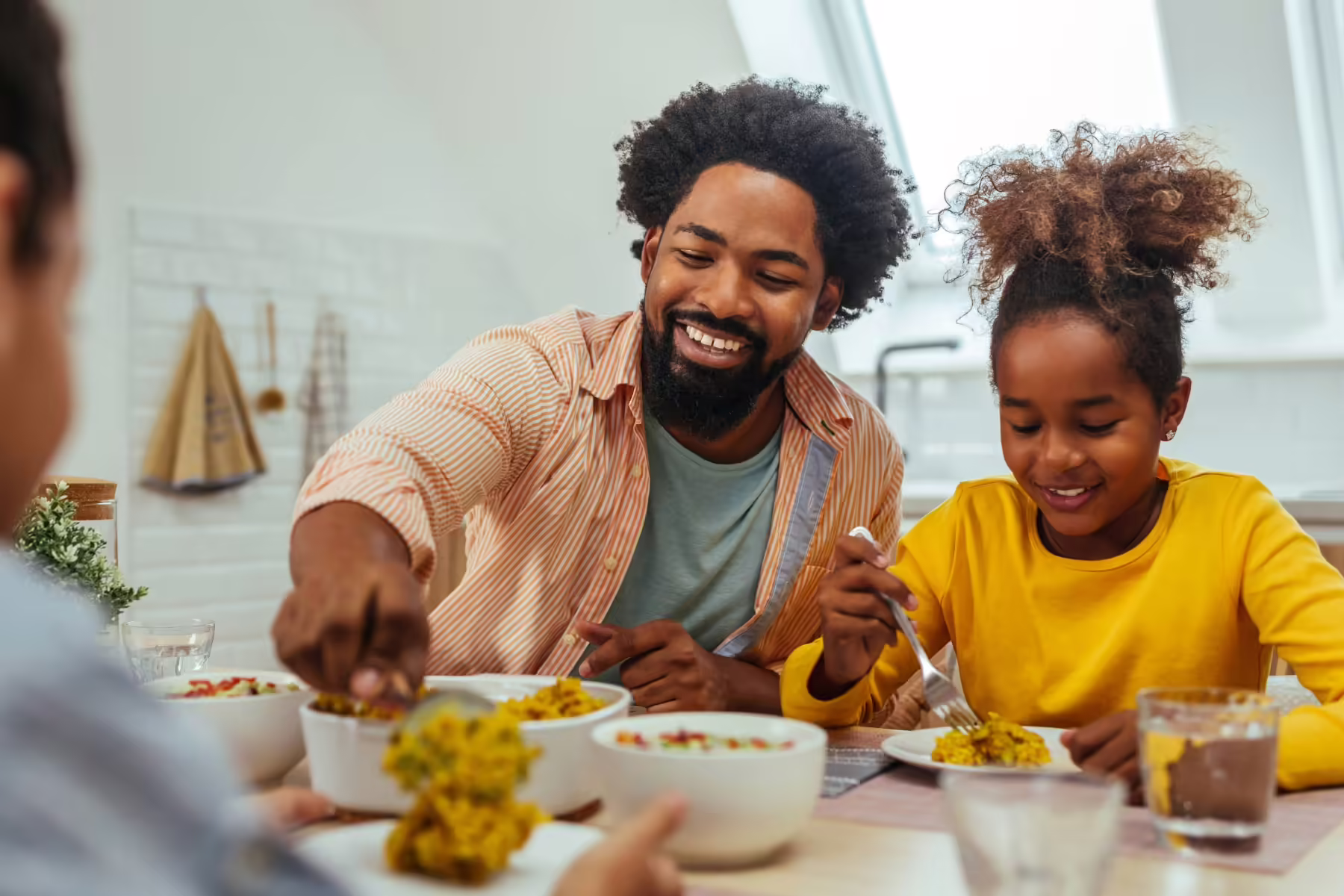 father and teen daughter eating food at table