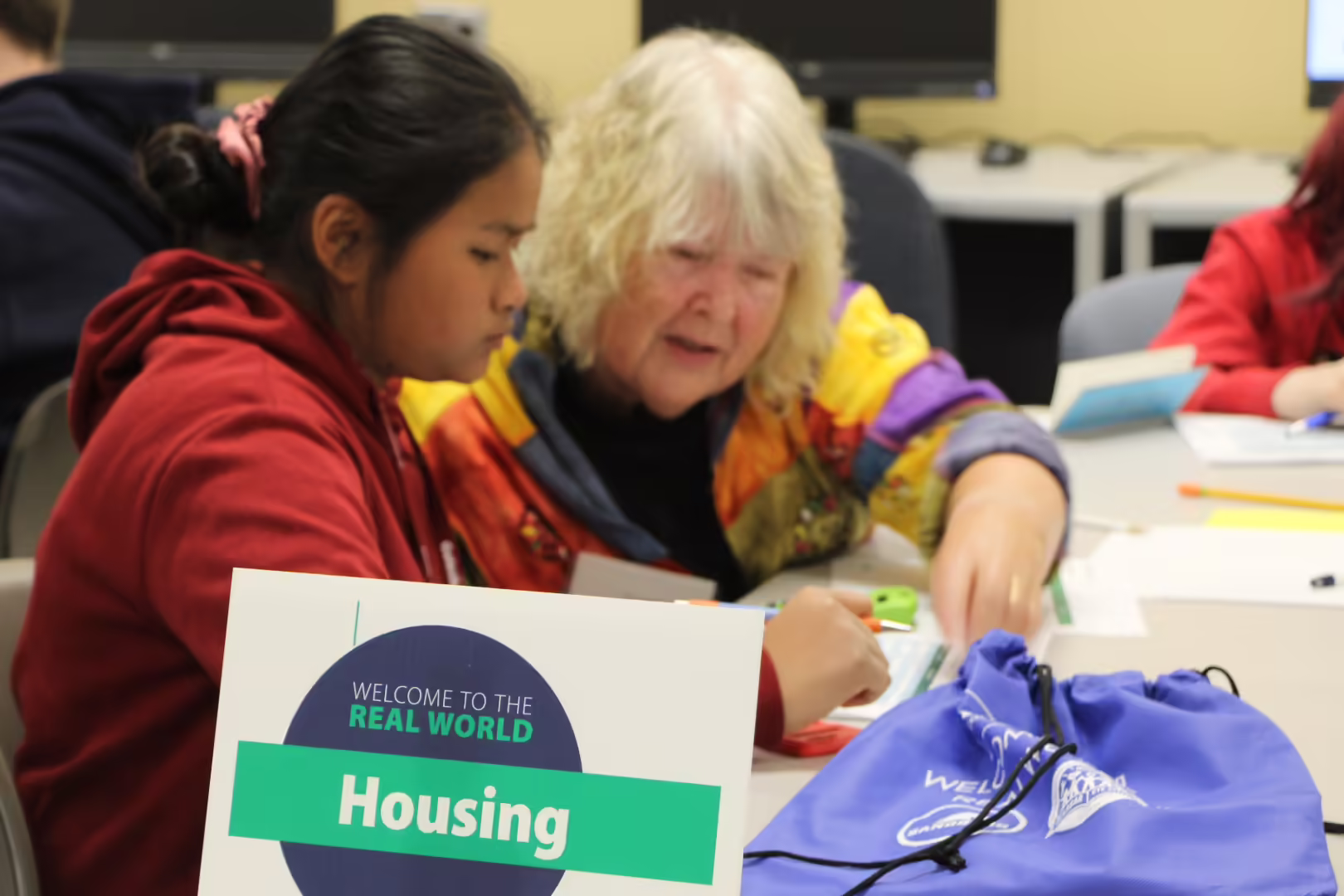 A volunteer helps a student at the housing station during Welcome to the Real World.