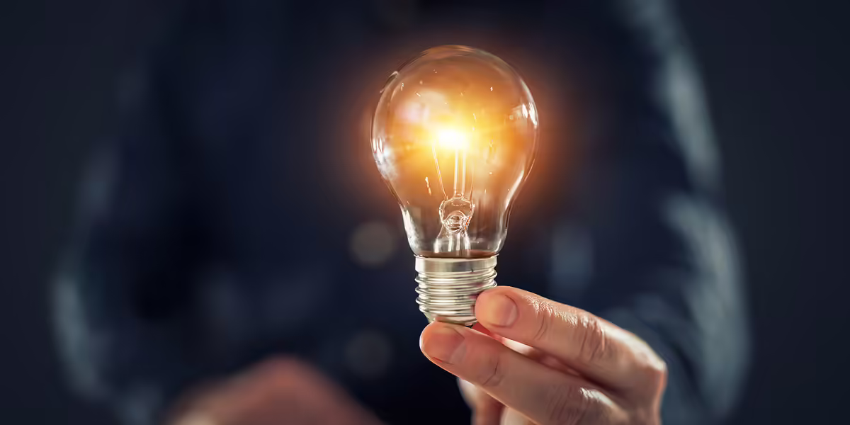 a hand holding a lit lightbulb