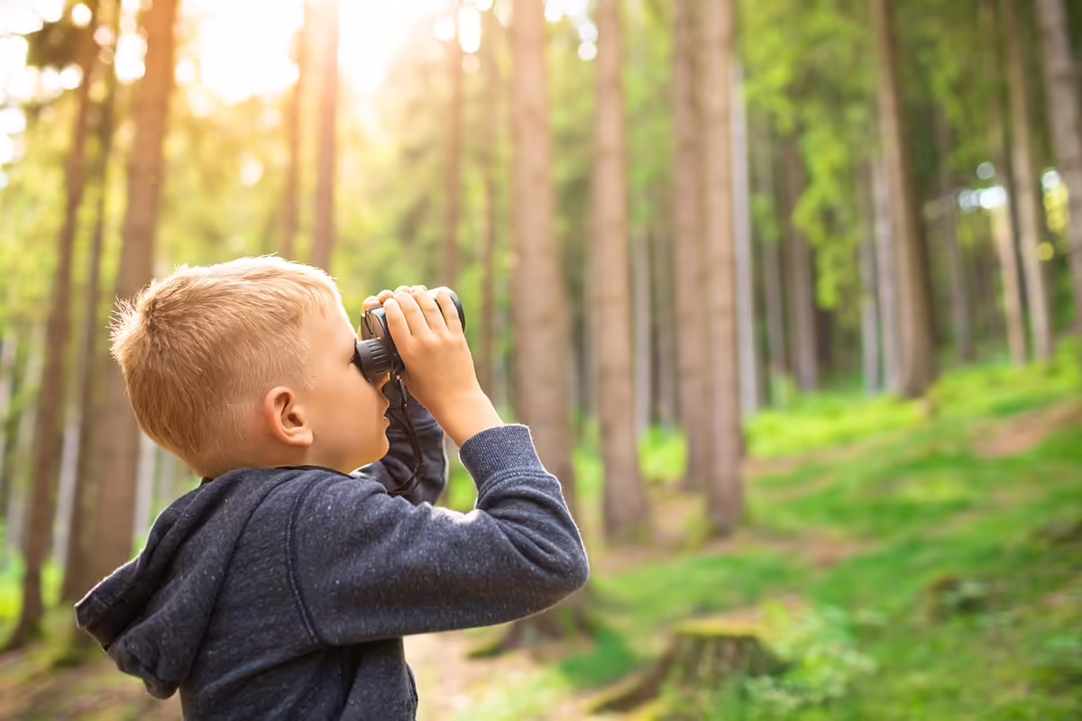 a boy in the woods with binoculars 