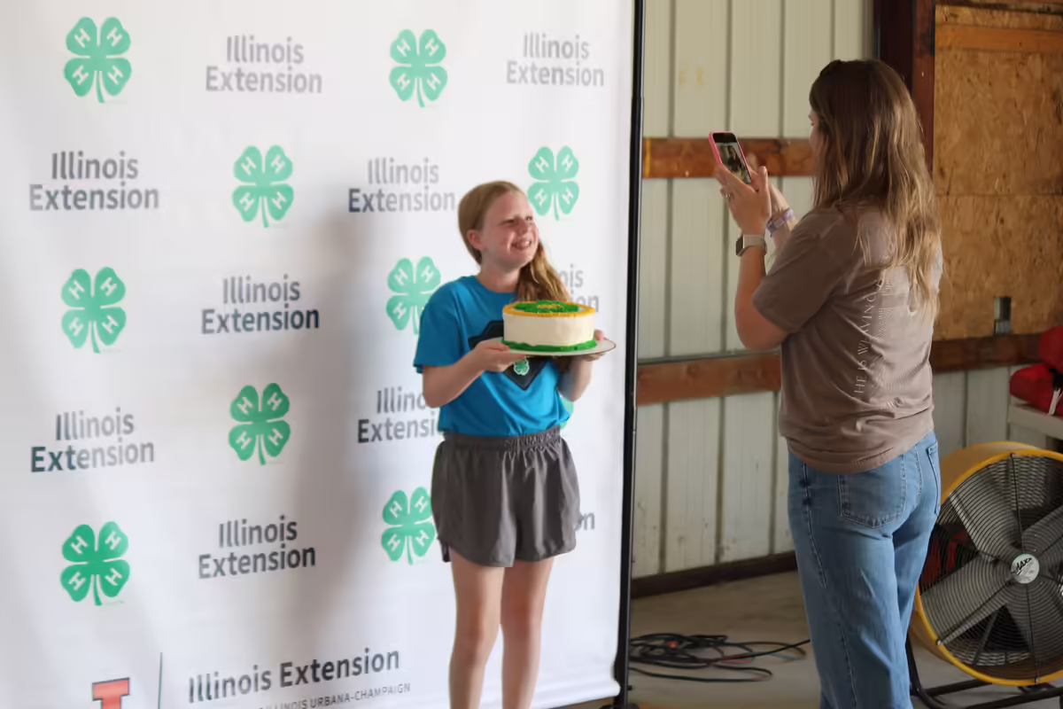 4-H member poses with decorated cake for her fair entry