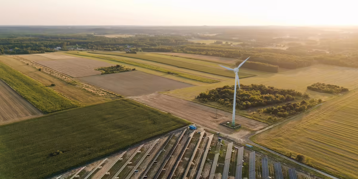An aerial view of a wind turbine surrounded by fields