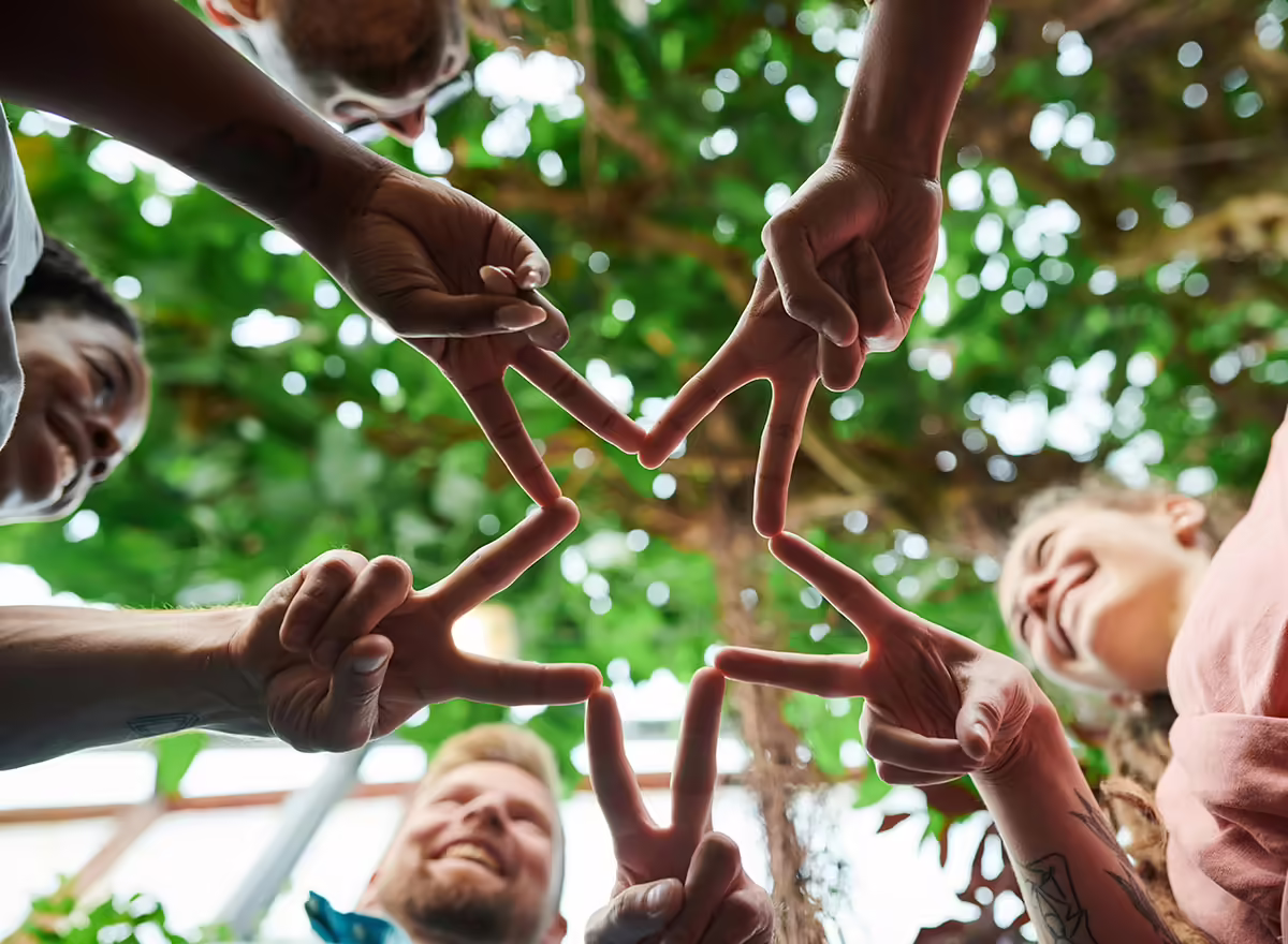 people standing in circle forming star with their hands