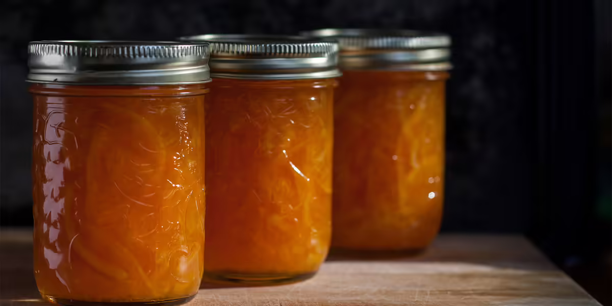 processed jars of orange marmelade in clear jars with two piece lids