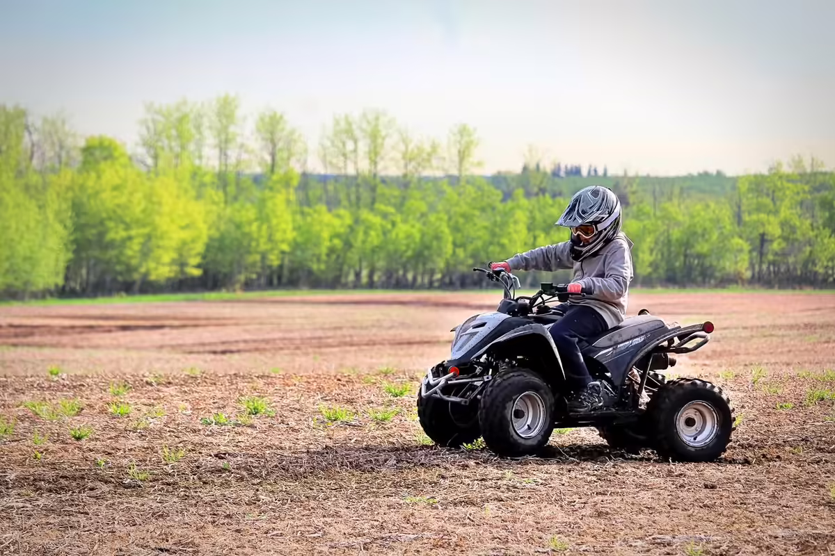 youg boy riding an all-errain vehicle in a field