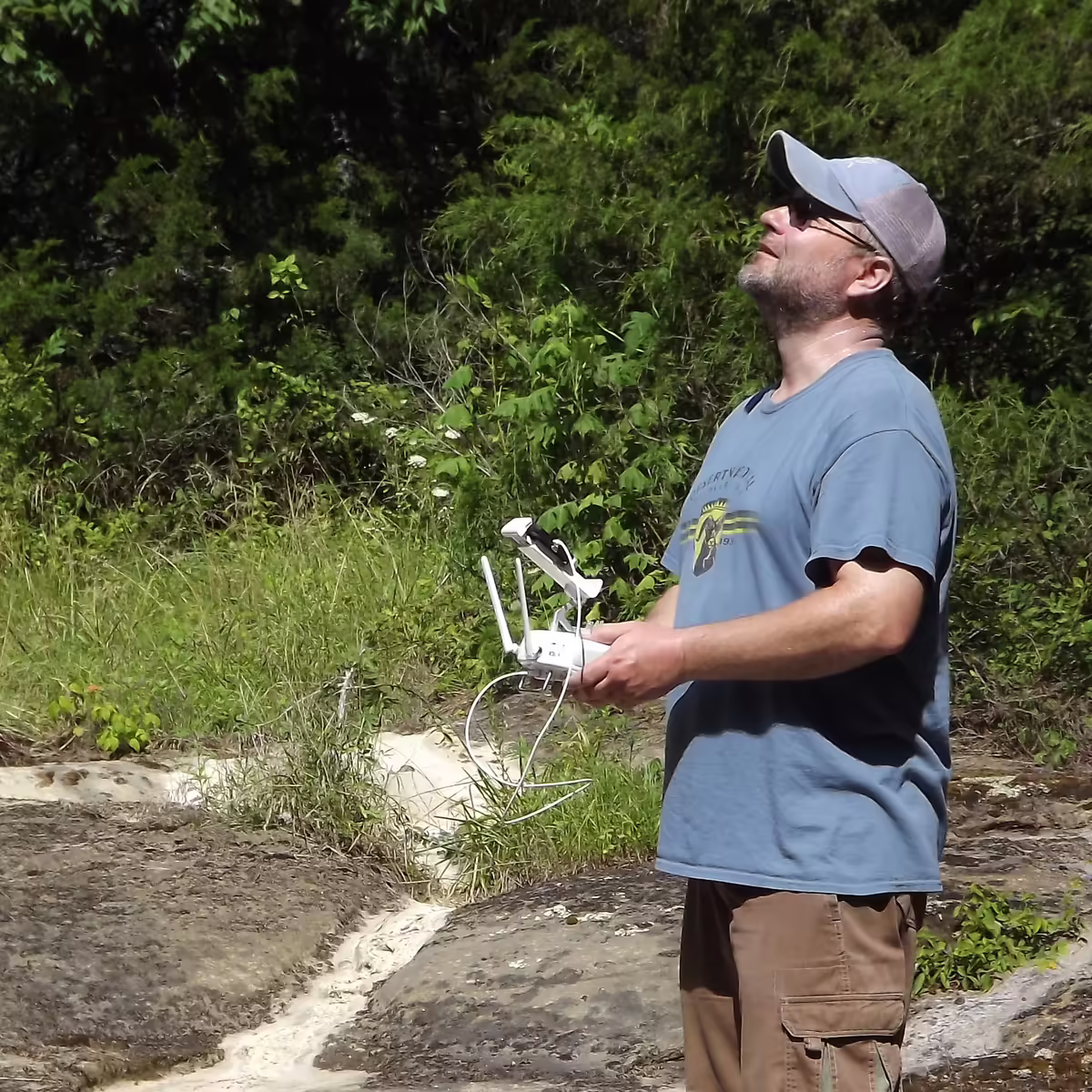 man holding a drone looks upward