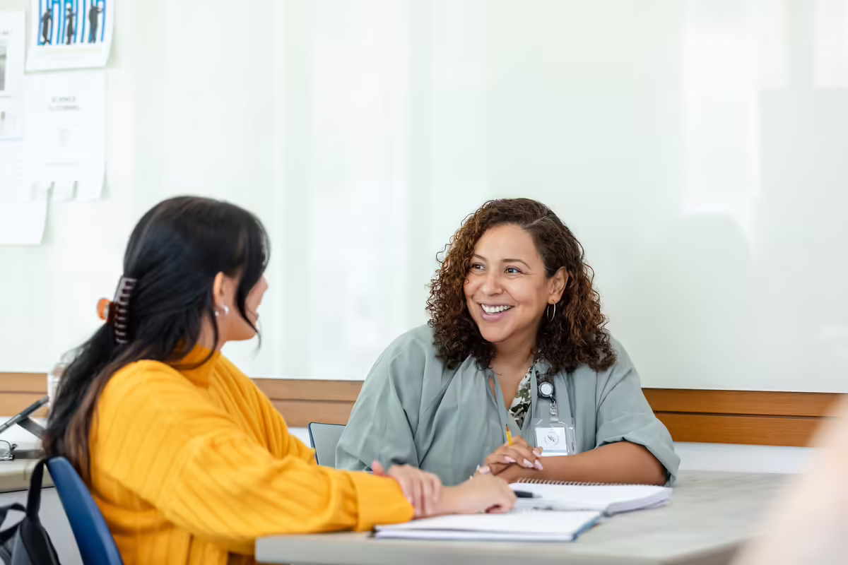 two women sitting at a table talking together
