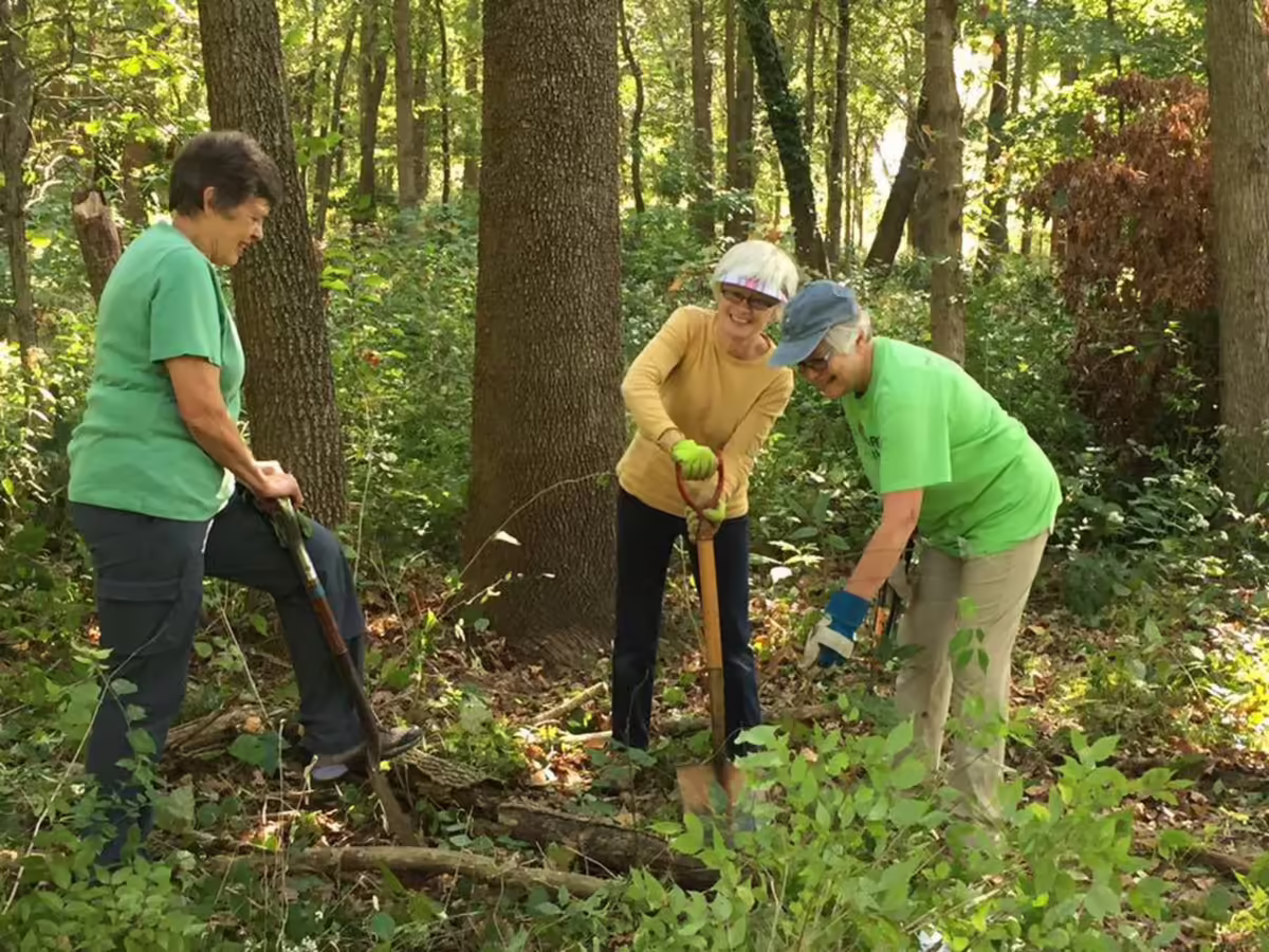 A group of women outside holding shovels and gardening.