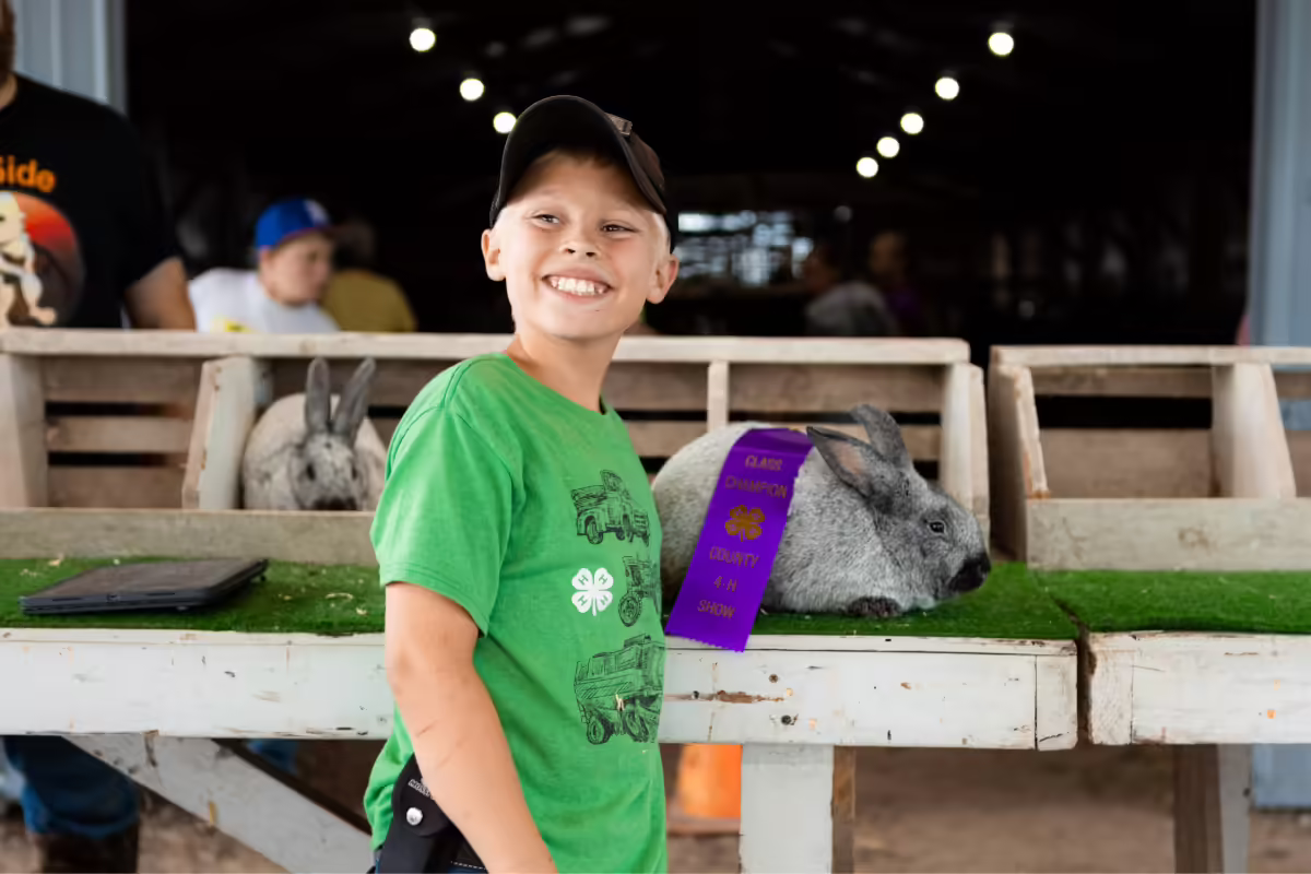 4-H member looks at the camera and poses with his 4-H rabbit