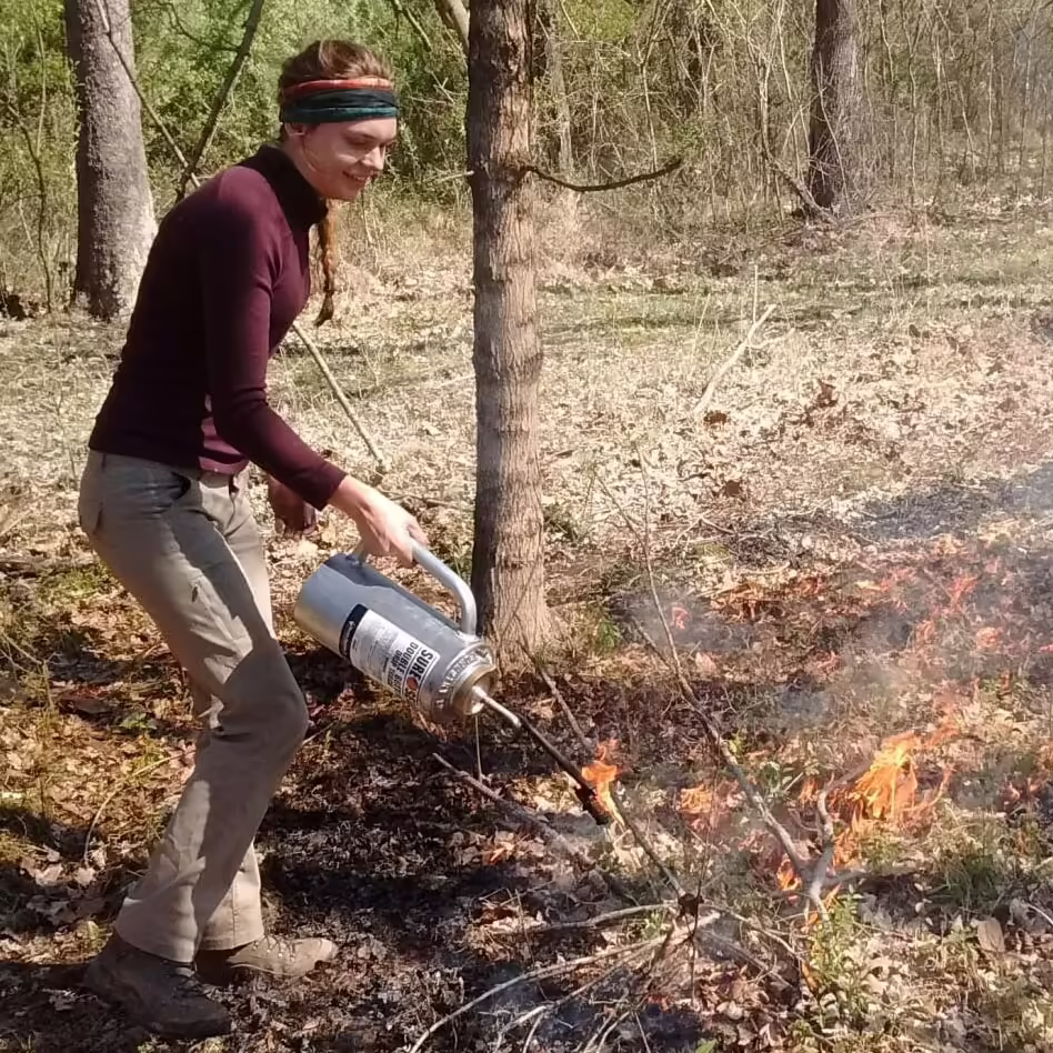 woman with flame torch creates fire line in forest