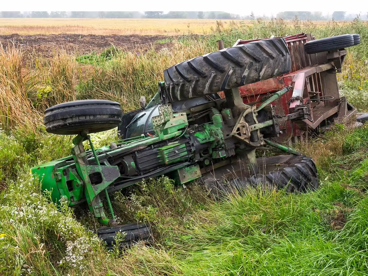 overturned tractor and cart near side of road