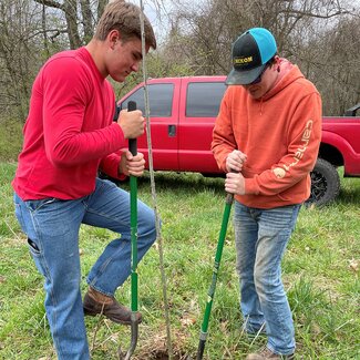 Youth planting a trees with red truck in background