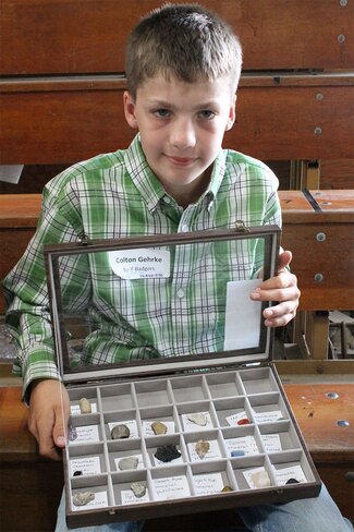 boy holding rocks in display case