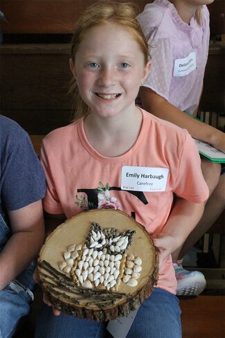 girl in peach shirt showing her owl project.