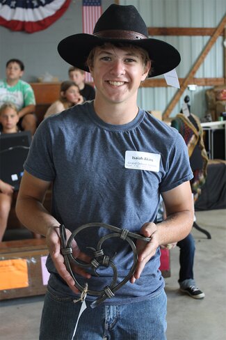boy in black cowboy hat and blue shirt holding a metal sculpture