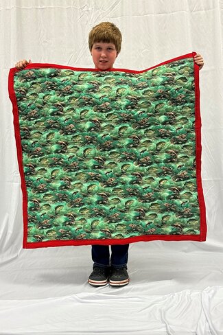 boy holding up green and red quilt