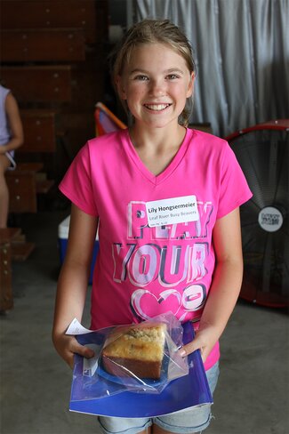 girl in pink shirt holding plate of bread