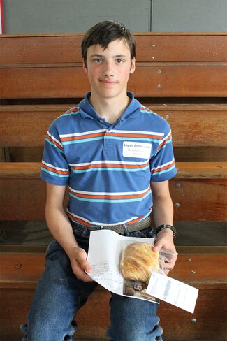 boy in blue striped shirt holding plate of bread