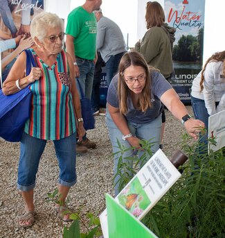 An Extension employee points to a plant in the demonstration garden to show a woman a caterpillar
