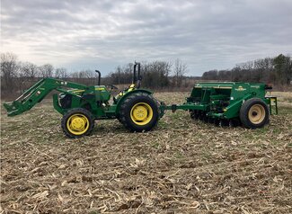 green tractor with a green no-till drill attached