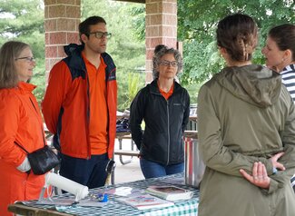 Group of three people visiting a program demonstration table.