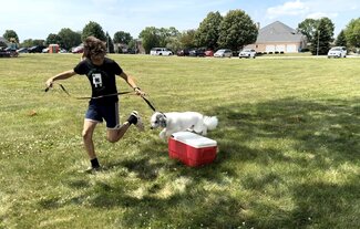 Connor Medina with their dog jumping over a cooler