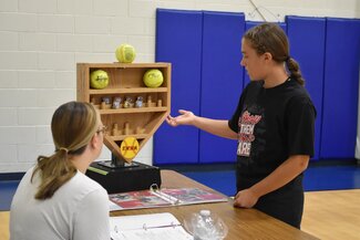 teenage girl in a black t-shirt showing her softball display case