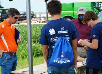 A group of youth looking at a book to identify crop-related insects.