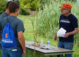 Three people having a conversation around Miscanthus plants. 