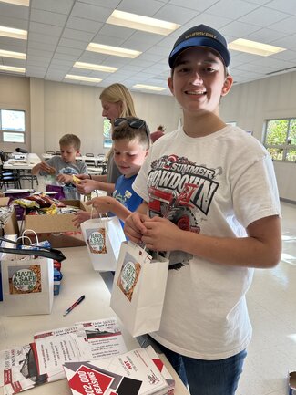 youth smiles to the camera while packing bags