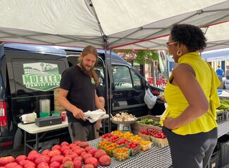 A farmer helps a customer at the farmers market