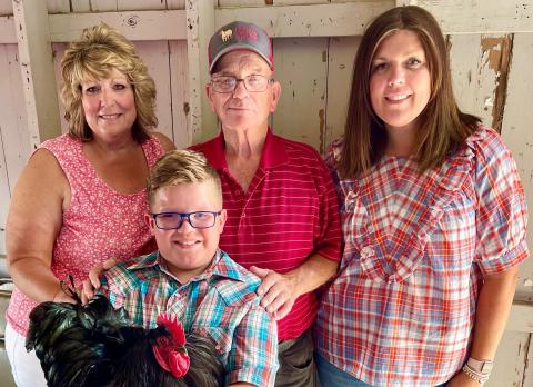 4-H member Connor Lind holding a chicken and surrounded by family