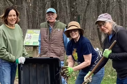 People in a forest pose with a bin and tools