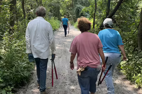 People walk down a trail with garden tools