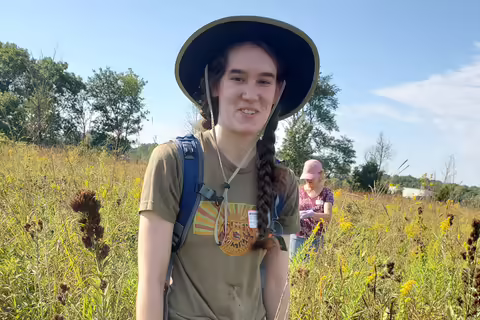 A woman stands in a prairie field