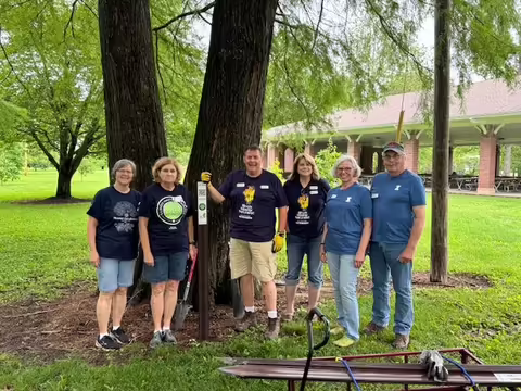 A group of people standing in front of a tree