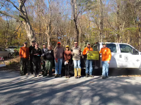 People in front of a truck in a forest wearing work clothes