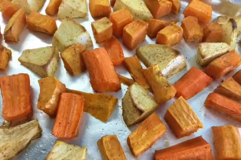 cubed and roasted carrot, apple, and potato on a baking sheet