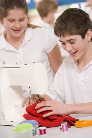 2 Teens at a sewing machine.