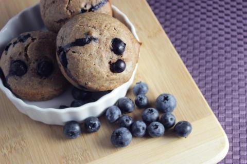 Muffin studded with blueberries on cutting board