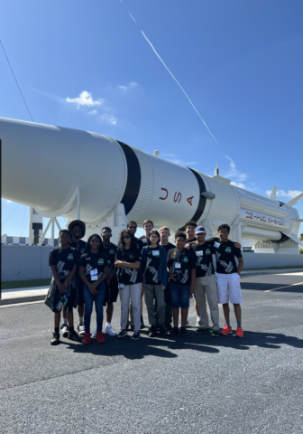 youth pose in front of a large rocket