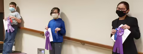 three youth with ribbons and certificates