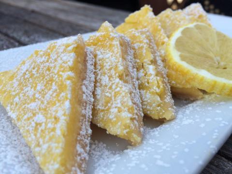 Lemon bar triangles with lemon slice on white plate