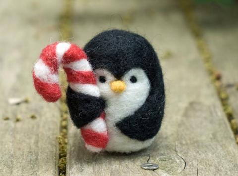 Felt penguin holding a candy cane. 