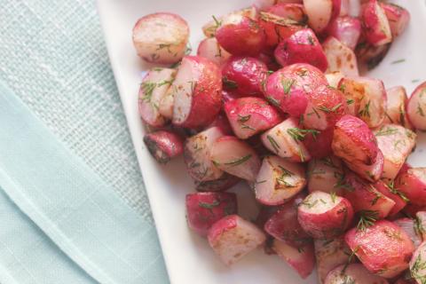 Sautéed radishes on white plate and blue placemat
