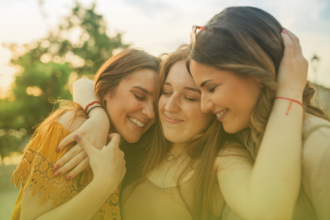 3 teens smiling and hugging