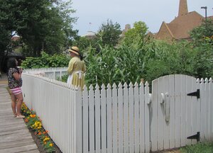 two women standing on each side of a white fence