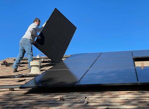 person installing solar panels on home