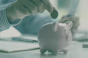 hand putting quarter into top of piggy bank