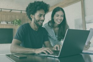 smiling young couple checking information on laptop